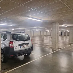 Ondergrondse parkeergarage met witte auto en betonnen pilaren