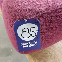 Blauwe prijssticker met nummer 85 op roze textiel