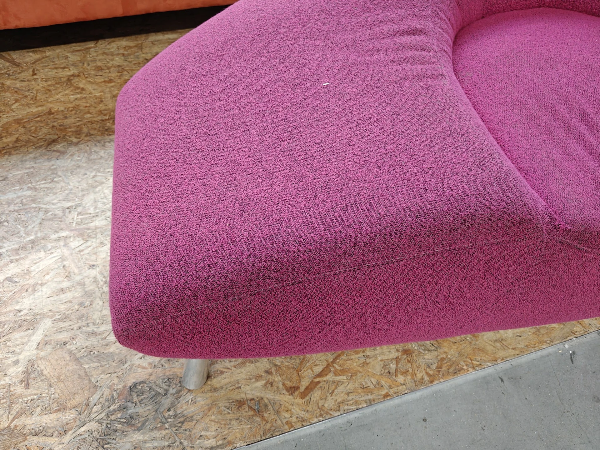 Roze/paarse stofkussen of poef op metalen poten, gedeeltelijk op kurk- en betonvloer