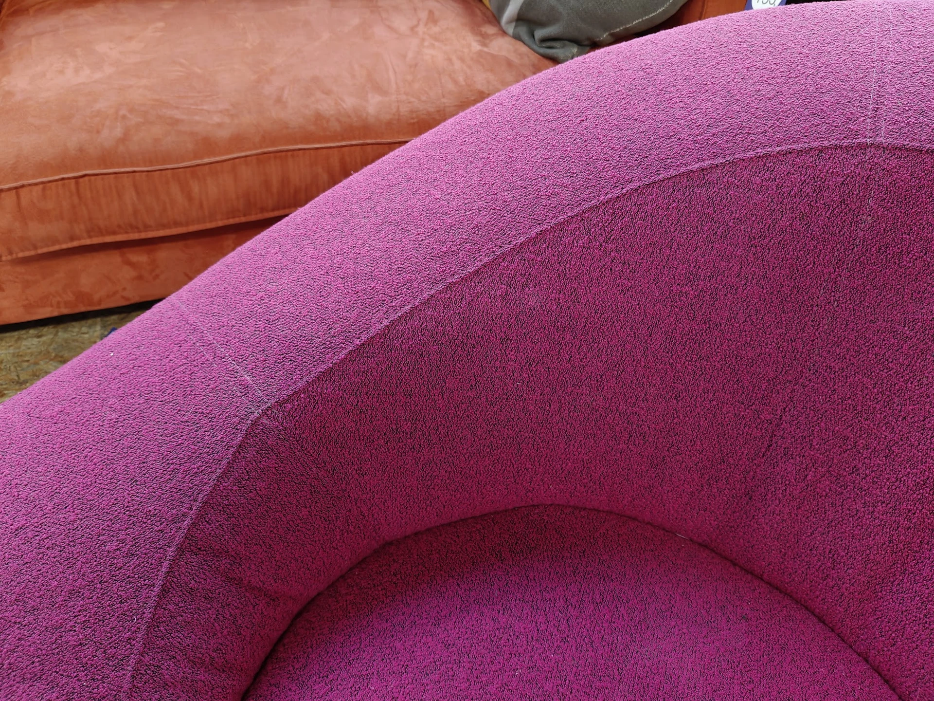 Close-up van een roze/magenta gewatteerde fauteuil met ronde vormen en textielkwaliteit zichtbaar