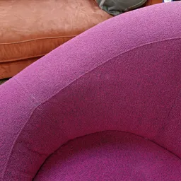 Close-up van een roze/magenta gewatteerde fauteuil met ronde vormen en textielkwaliteit zichtbaar