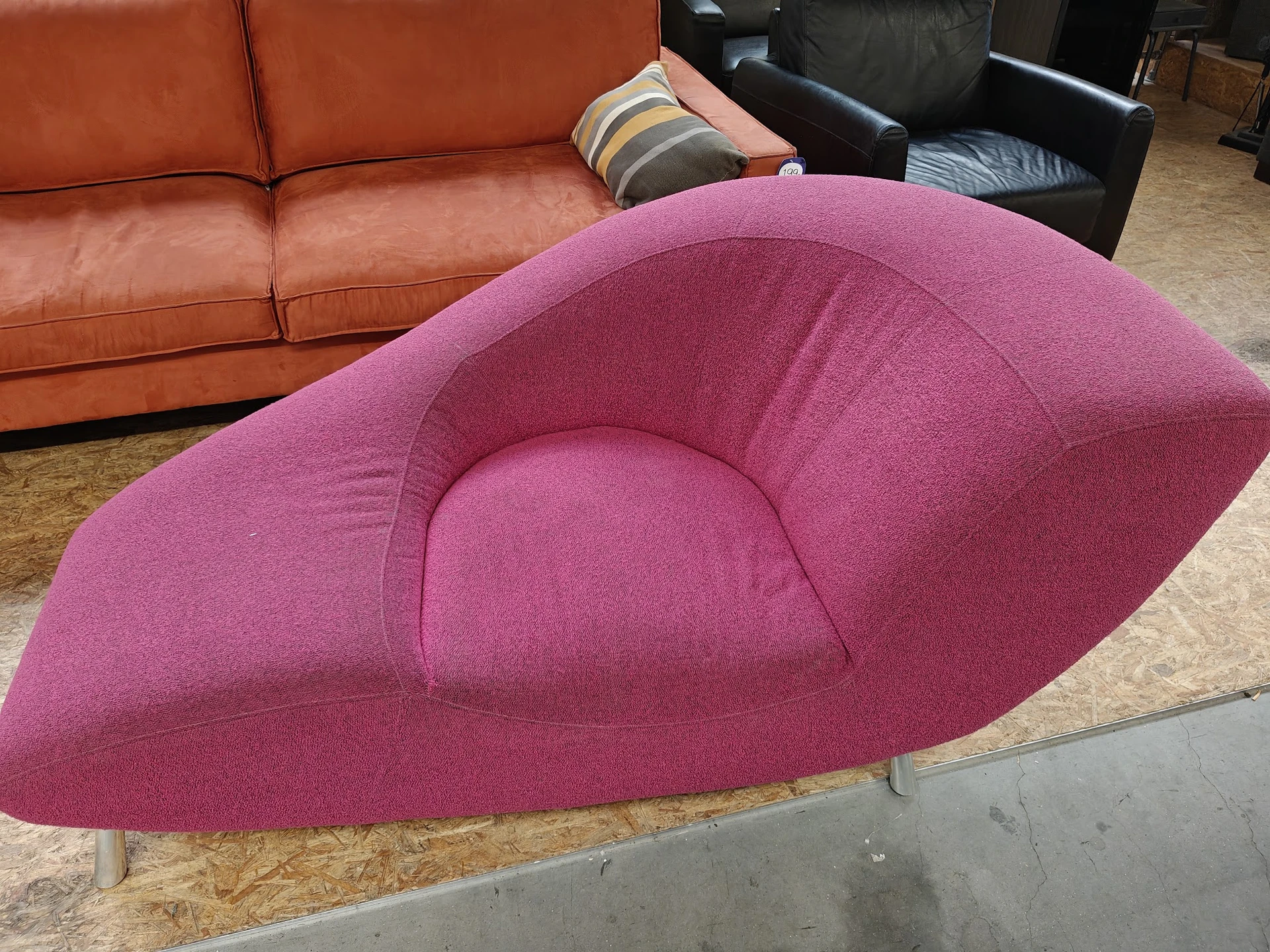 Roze/paars fauteuil met organische vormen en metalen poten in een kringloopwinkel