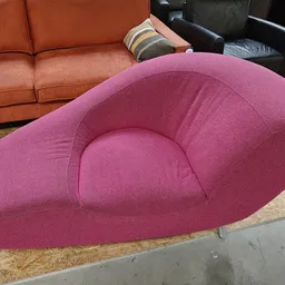 Roze/paars fauteuil met organische vormen en metalen poten in een kringloopwinkel