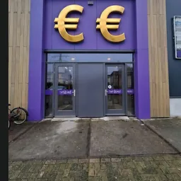 Paarse gevel met gouden letters en grijze deuren van kringloopwinkel