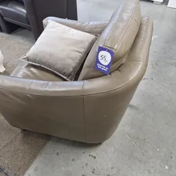 Beige lederen fauteuil met kussen en blauwe prijskaartje nummer 55