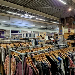 Rekken met tweedehands kleding op hangers in een kringloopwinkel