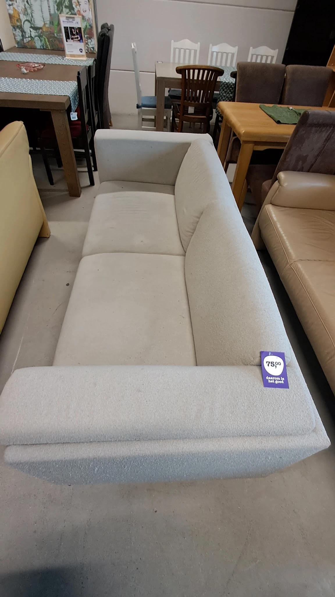 Tweedehands crèmekleurige stof bank of sofa met zichtbare vlekken en een prijskaartje