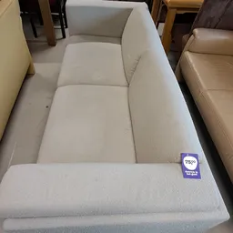 Tweedehands crèmekleurige stof bank of sofa met zichtbare vlekken en een prijskaartje