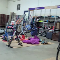 Winkelvloer met fietsen, stellingen met kleding en diverse spullen, onscherp beeld