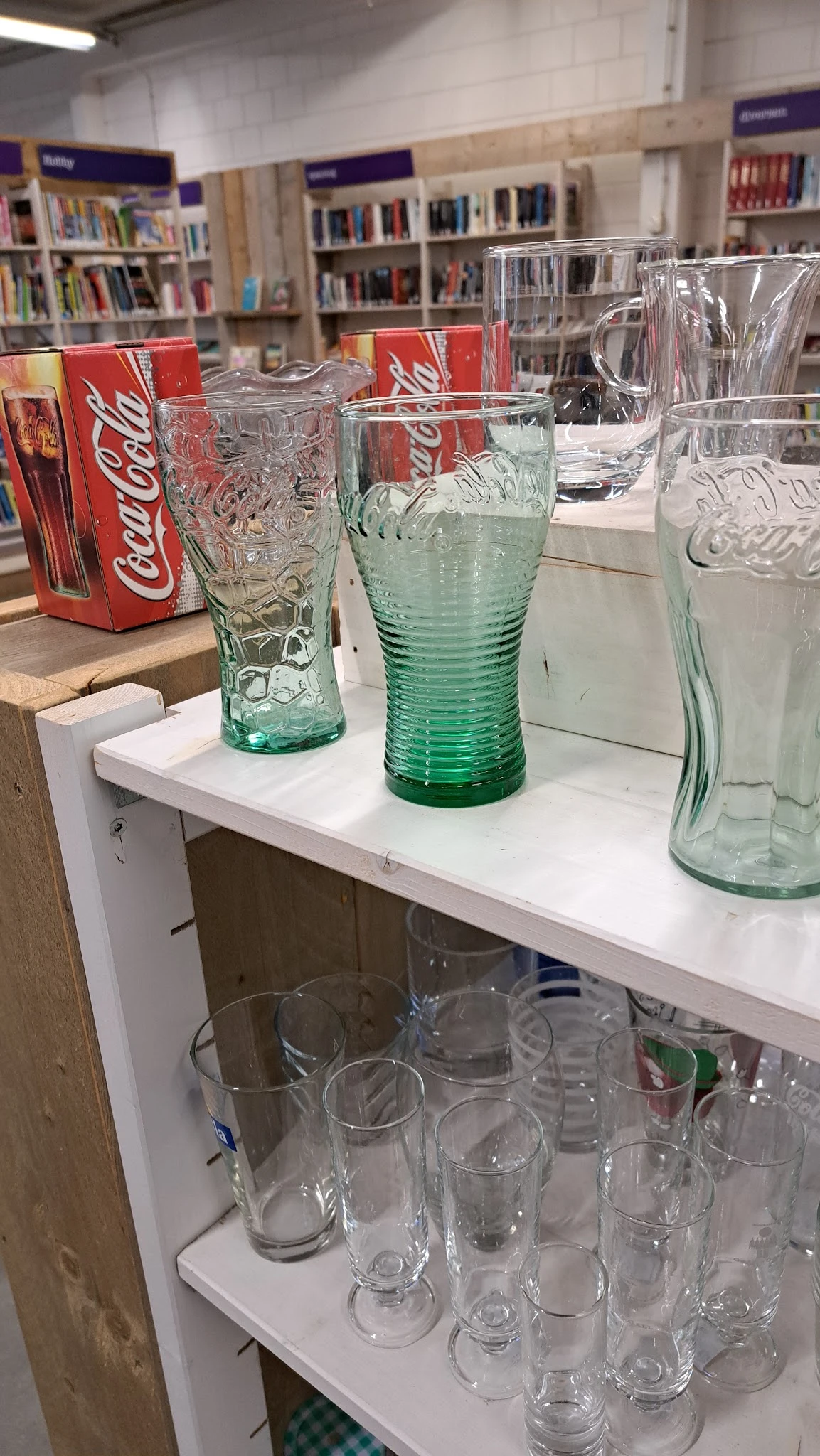 Groene glazen bekers en drinkglazen op een witte plank in de winkel