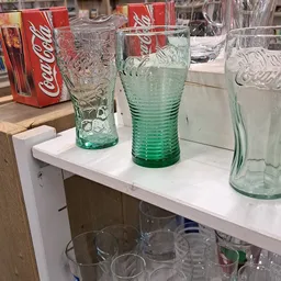 Groene glazen bekers en drinkglazen op een witte plank in de winkel