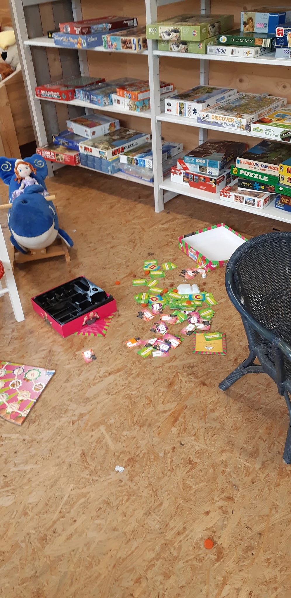 Kinderspeelhoek met speelgoed, een roze gereedschapskist, blauwe bal en zwarte stoel op kurkvloer