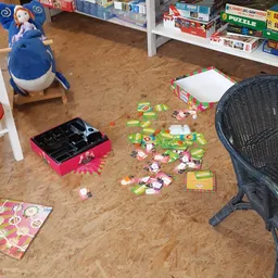 Kinderspeelhoek met speelgoed, een roze gereedschapskist, blauwe bal en zwarte stoel op kurkvloer
