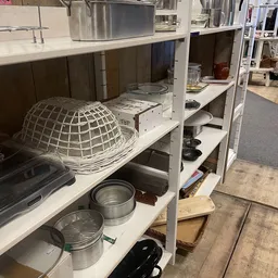 Witte stellingen met huishoudelijke artikelen zoals pannen, schalen en keukenspullen