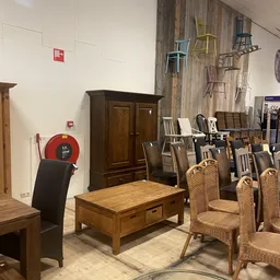Winkelvloer met houten meubels: tafels, stoelen en een kast, naast een rode brandblusser