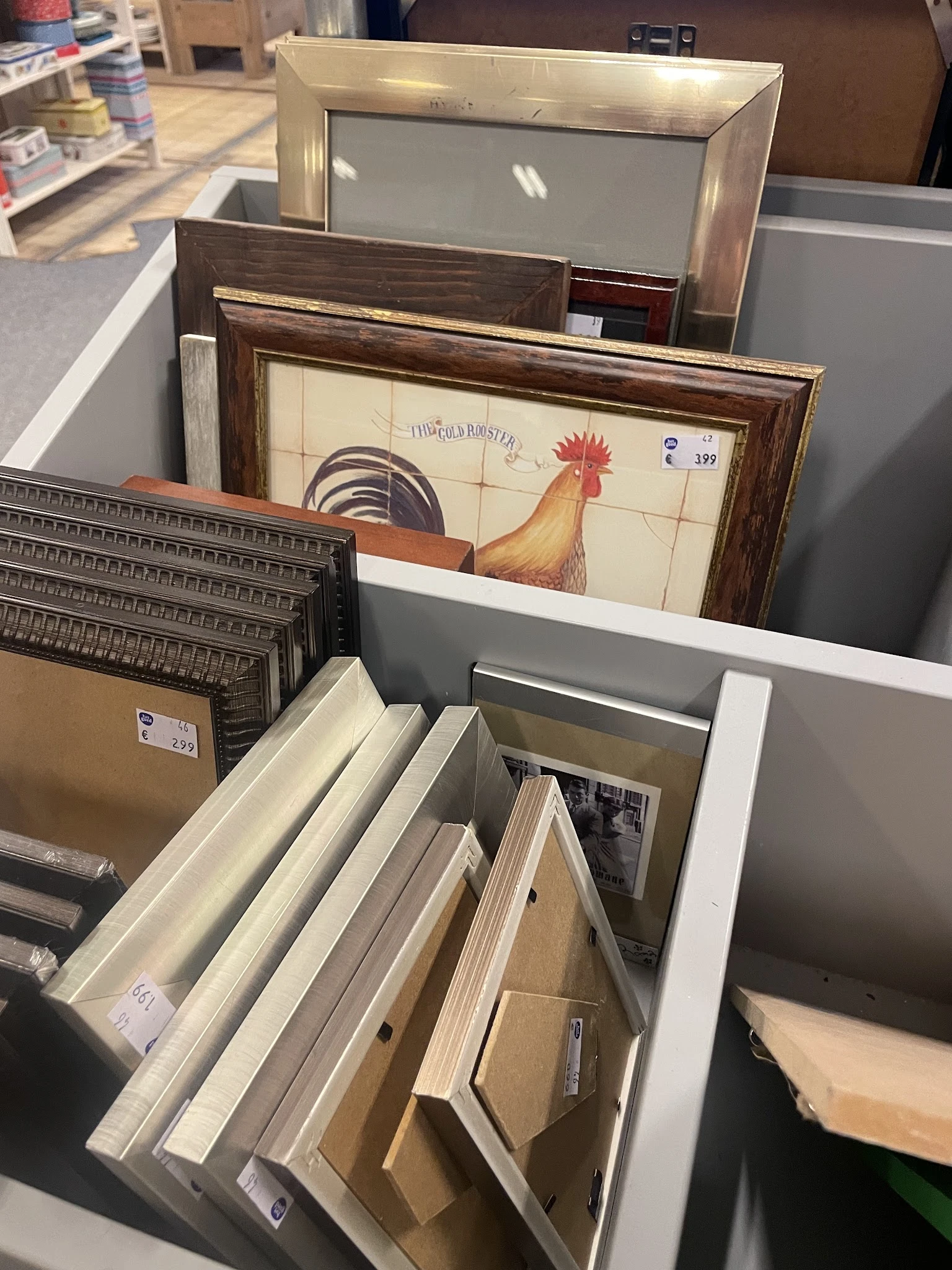 Diverse tweedehands artikelen: schilderijen, houten kisten, kastjes en ander huishoudelijk goed uitgestald in de winkel