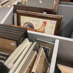 Diverse tweedehands artikelen: schilderijen, houten kisten, kastjes en ander huishoudelijk goed uitgestald in de winkel