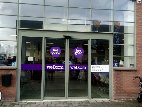 Glazen winkelpui met paarse neonletters 'het goed' en 'welkom' op donkere achtergrond