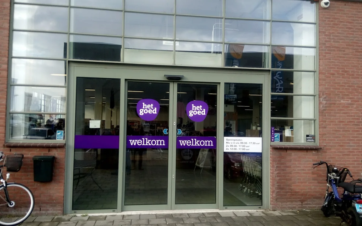 Glazen winkelpui met paarse neonletters 'het goed' en 'welkom' op donkere achtergrond