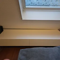 Witte wandmontage kast met twee lades onder een dakraam in een slaapkamer