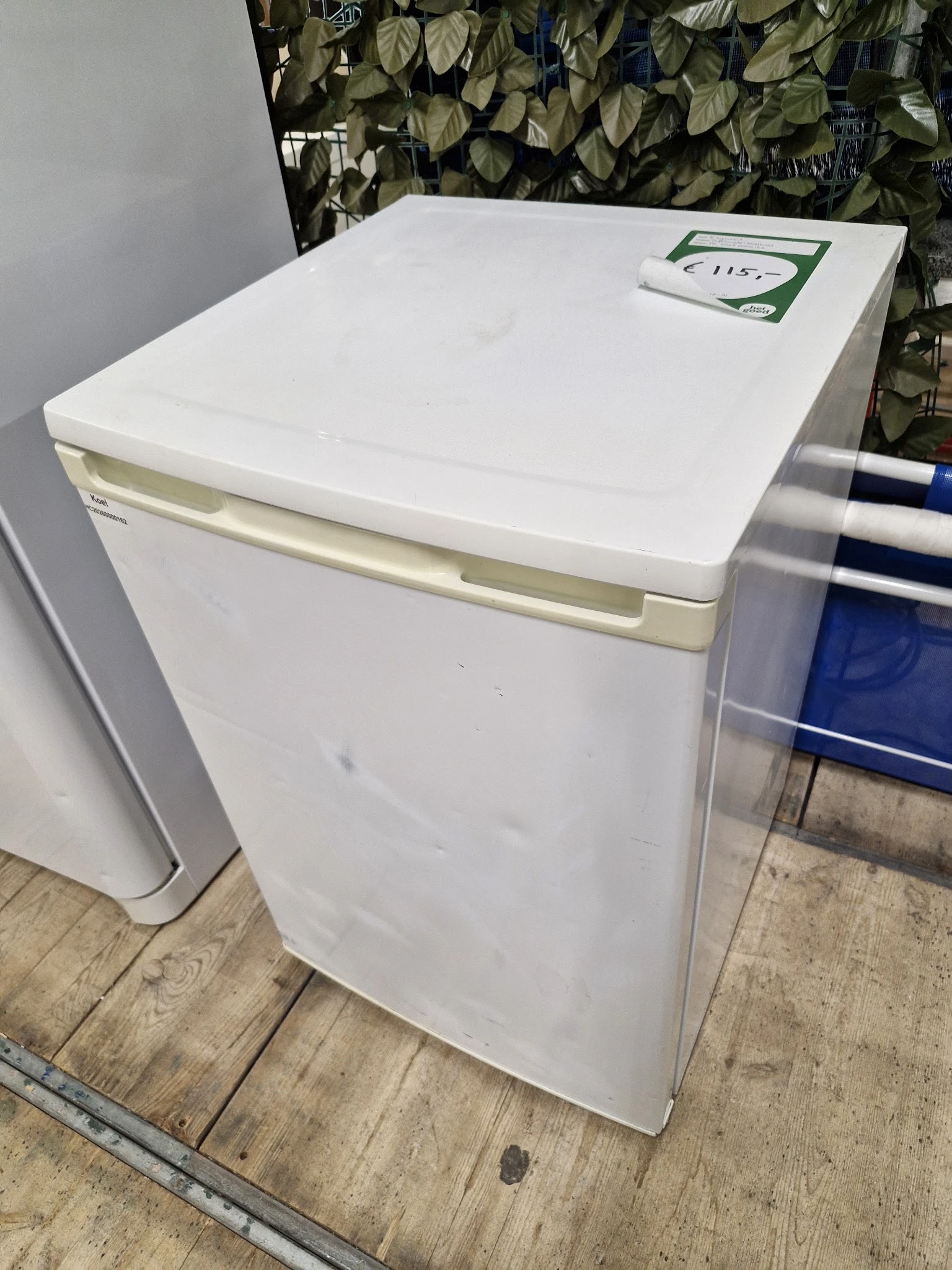Witte tafelmodel koelkast met beige handgreep, close-up van voor- en zijkant