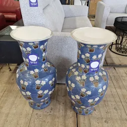 Twee blauwe decoratieve vazen met wit en goudkleurig bloempatroon en crèmekleurige randen