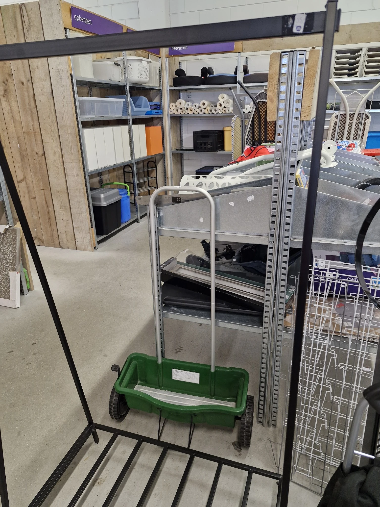Metalen stellingkast met grijze laden en groene kunststof krat eronder in een kringloopwinkel