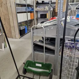 Metalen stellingkast met grijze laden en groene kunststof krat eronder in een kringloopwinkel