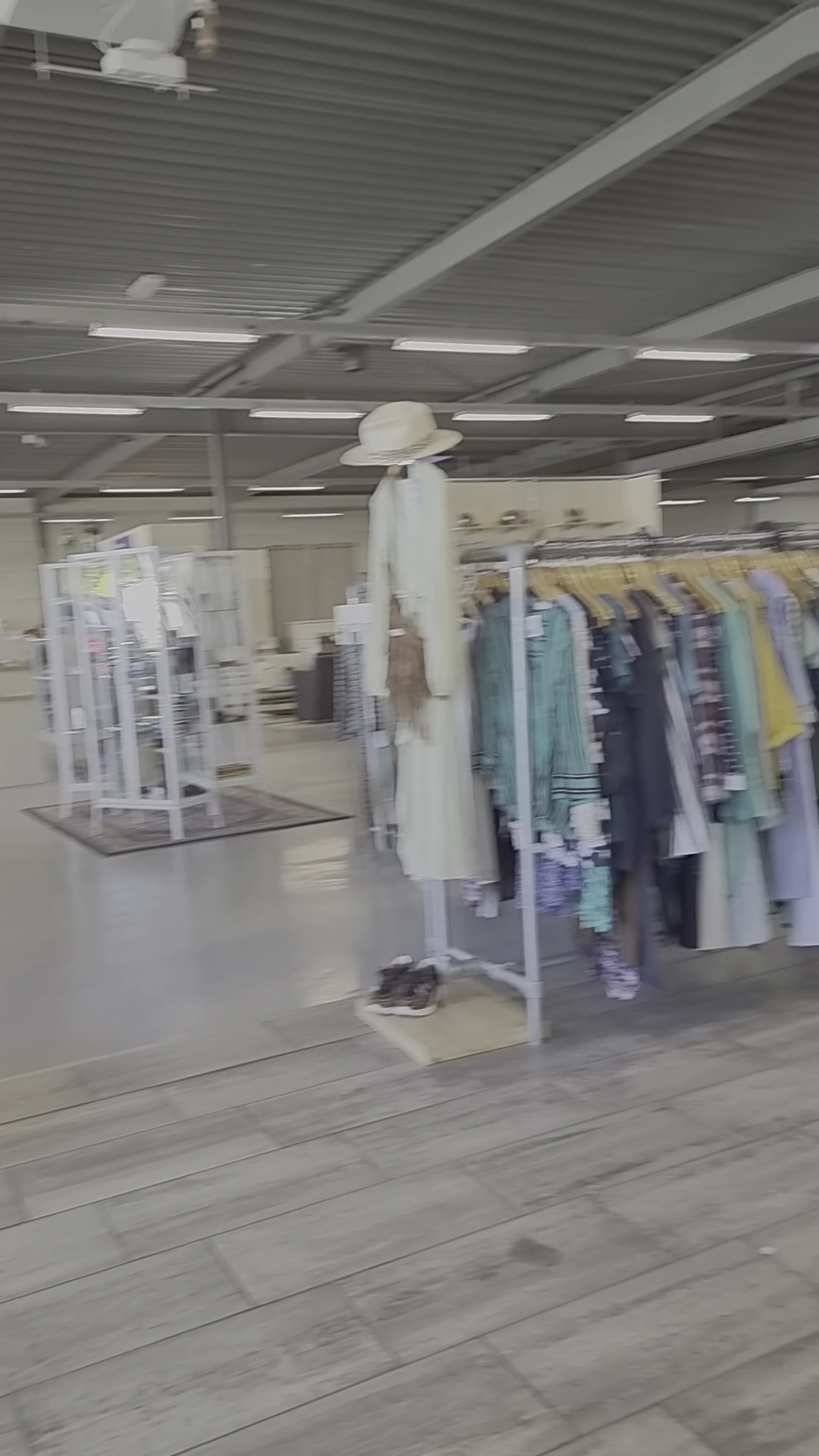 Rekken met tweedehands kleding in verschillende kleuren in een kringloopwinkel