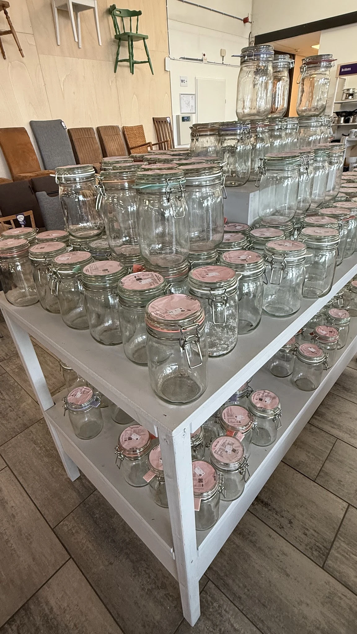 Glazen potten en jars met roze deksels uitgestald op witte tafels