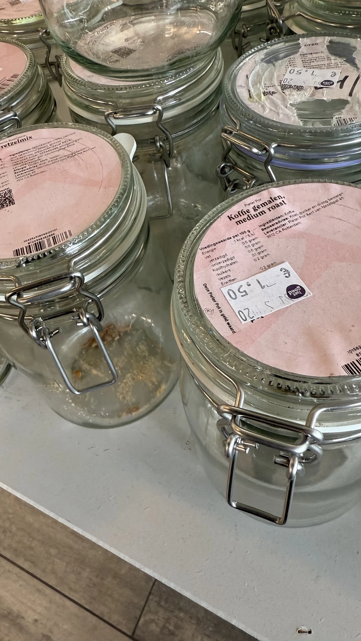 Twee glazen potten met metallieke beugels en roze etiketten met productinformatie