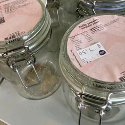Twee glazen potten met metallieke beugels en roze etiketten met productinformatie