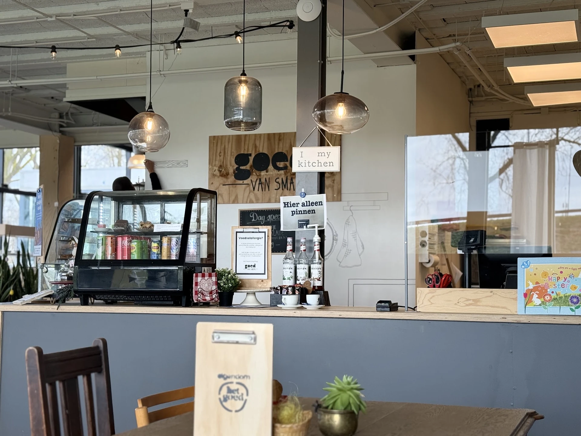 Koffiebar met espressomachine, hangende lampen en uitgestalde dranken- en etenswaar op de toonbank