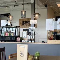 Koffiebar met espressomachine, hangende lampen en uitgestalde dranken- en etenswaar op de toonbank