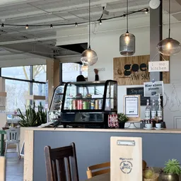 Toonbank met zwarte glazen vitrinekast, hangende lampen en houten bord met winkelnaam in moderne kringloopwinkel