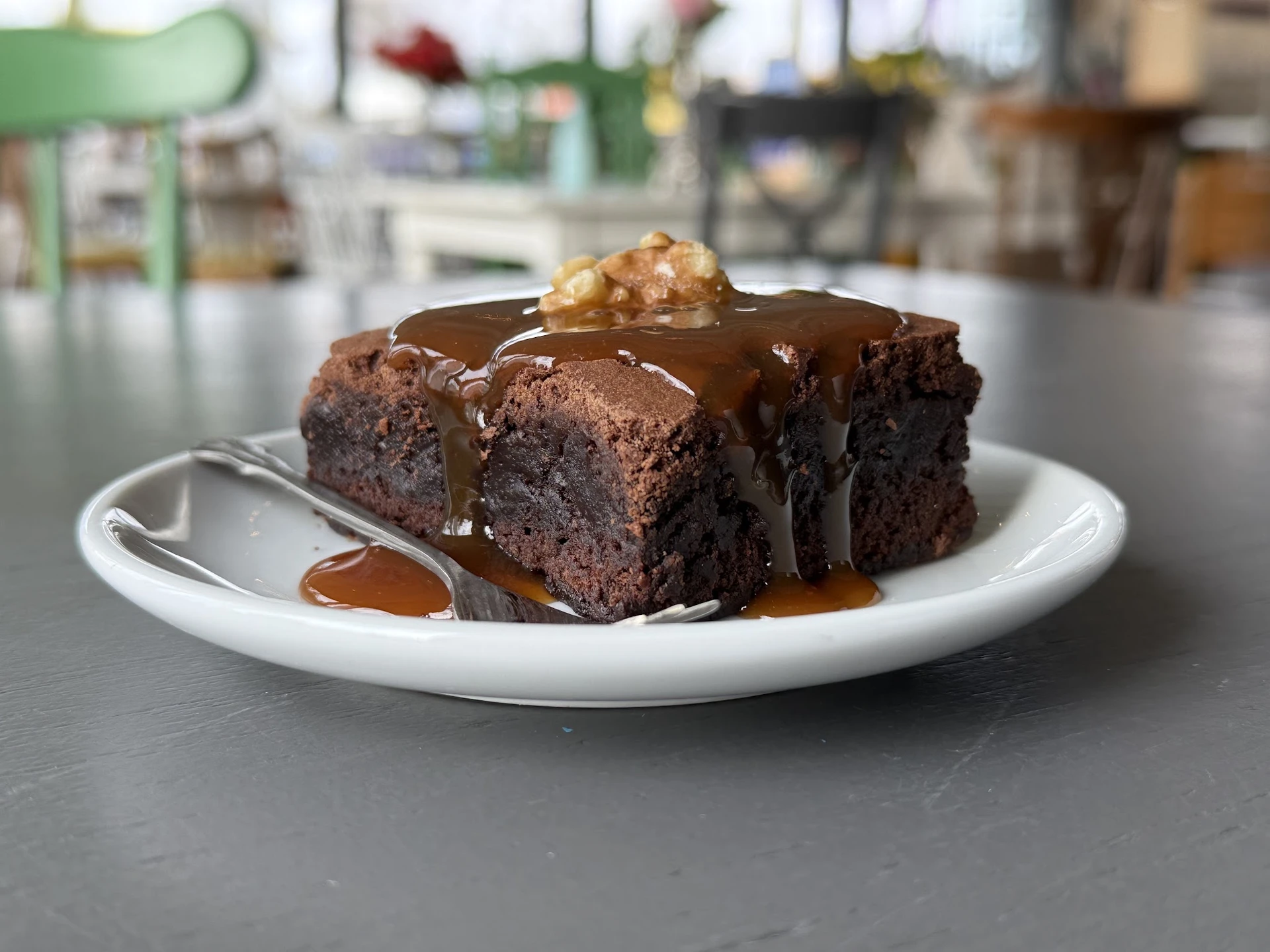 Chocolade browniecake met chocoladesaus en nootje op witte borden in de lunchroom