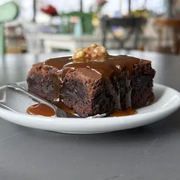 Chocolade browniecake met chocoladesaus en nootje op witte borden in de lunchroom