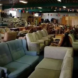 Winkelvloer met diverse tweedehands meubels, voornamelijk fauteuils en stoelen in verschillende kleuren en stijlen
