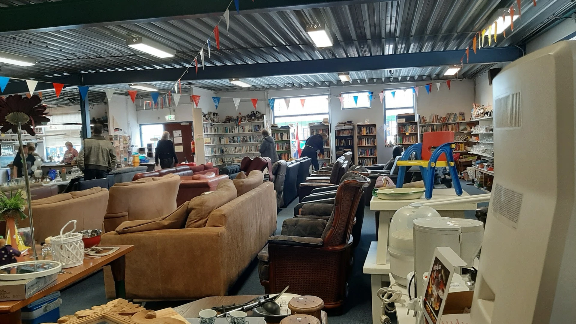 Ruime winkelvloer met zithoeken, boekenkasten, speelgoed en diverse meubels in kringloopwinkel