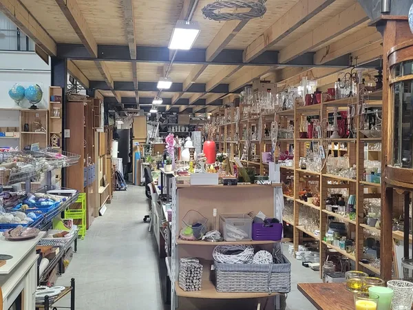 Overzicht van de winkelvloer met houten stellingen vol huishoudartikelen en diverse gebruiksgoederen