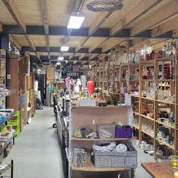 Overzicht van de winkelvloer met houten stellingen vol huishoudartikelen en diverse gebruiksgoederen