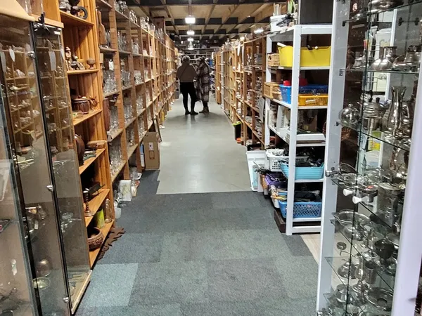 Winkelpad tussen stellingen met diverse spullen en articles in een kringloopwinkel