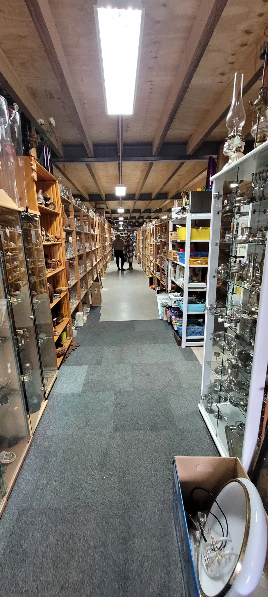 Winkelpad tussen stellingen met diverse spullen en articles in een kringloopwinkel