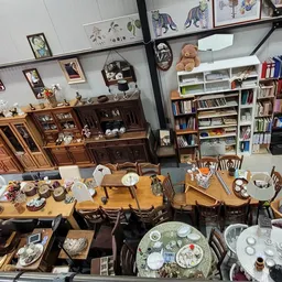 Overzicht van kringloopwinkel met boeken, servies, meubels en decoratieve items uitgestald op tafels en in kasten