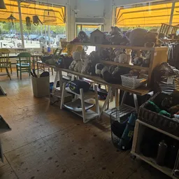 Winkelvloer met tafels vol tweedehands huishoudartikelen, stoelen en opbergruimte