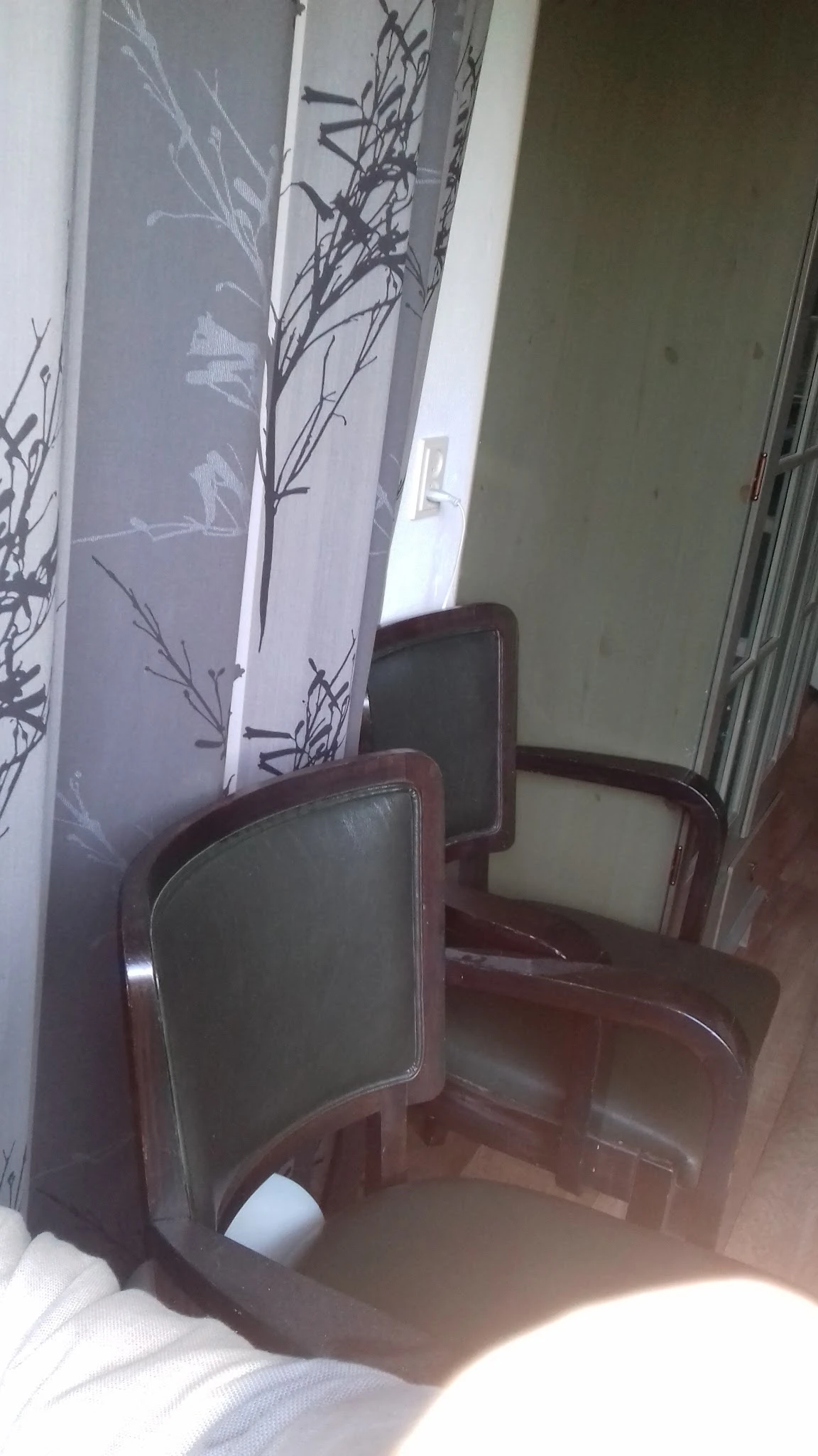 Twee houten stoelen met donker beklede zitting en rugleuning.