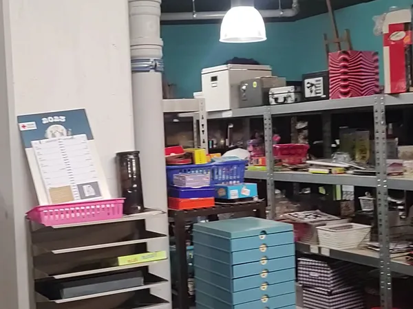 Winkelinterieur met metalen stellingen vol dozen, opbergmanden en huishoudelijke artikelen onder hanglamp