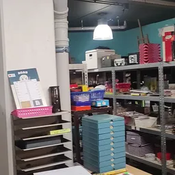 Winkelinterieur met metalen stellingen vol dozen, opbergmanden en huishoudelijke artikelen onder hanglamp