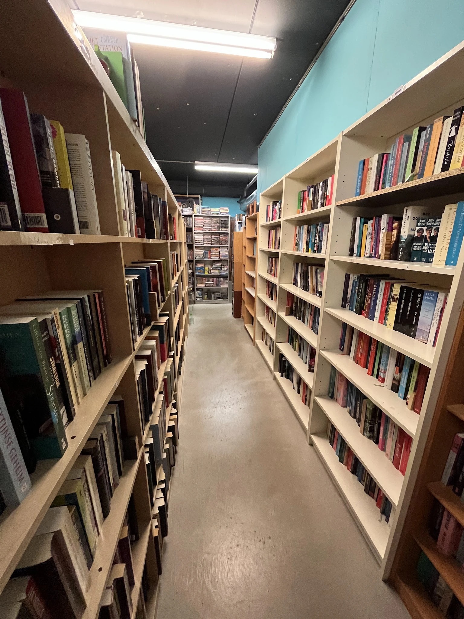 Lange gang tussen houten boekenkasten gevuld met tweedehands boeken in de winkel