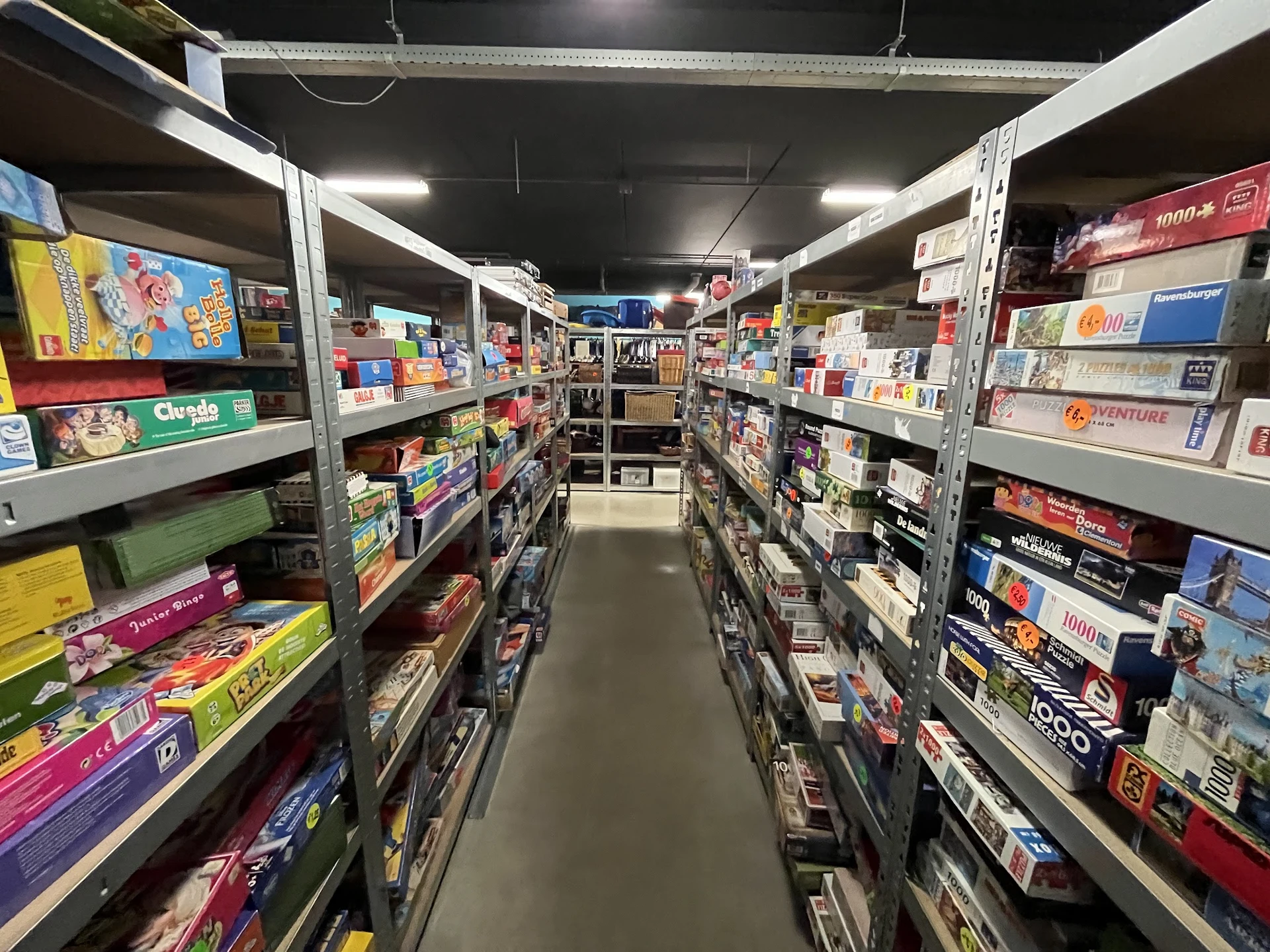 Winkelgang met metalen stellingen vol dozen en verpakkte goederen aan beide zijden